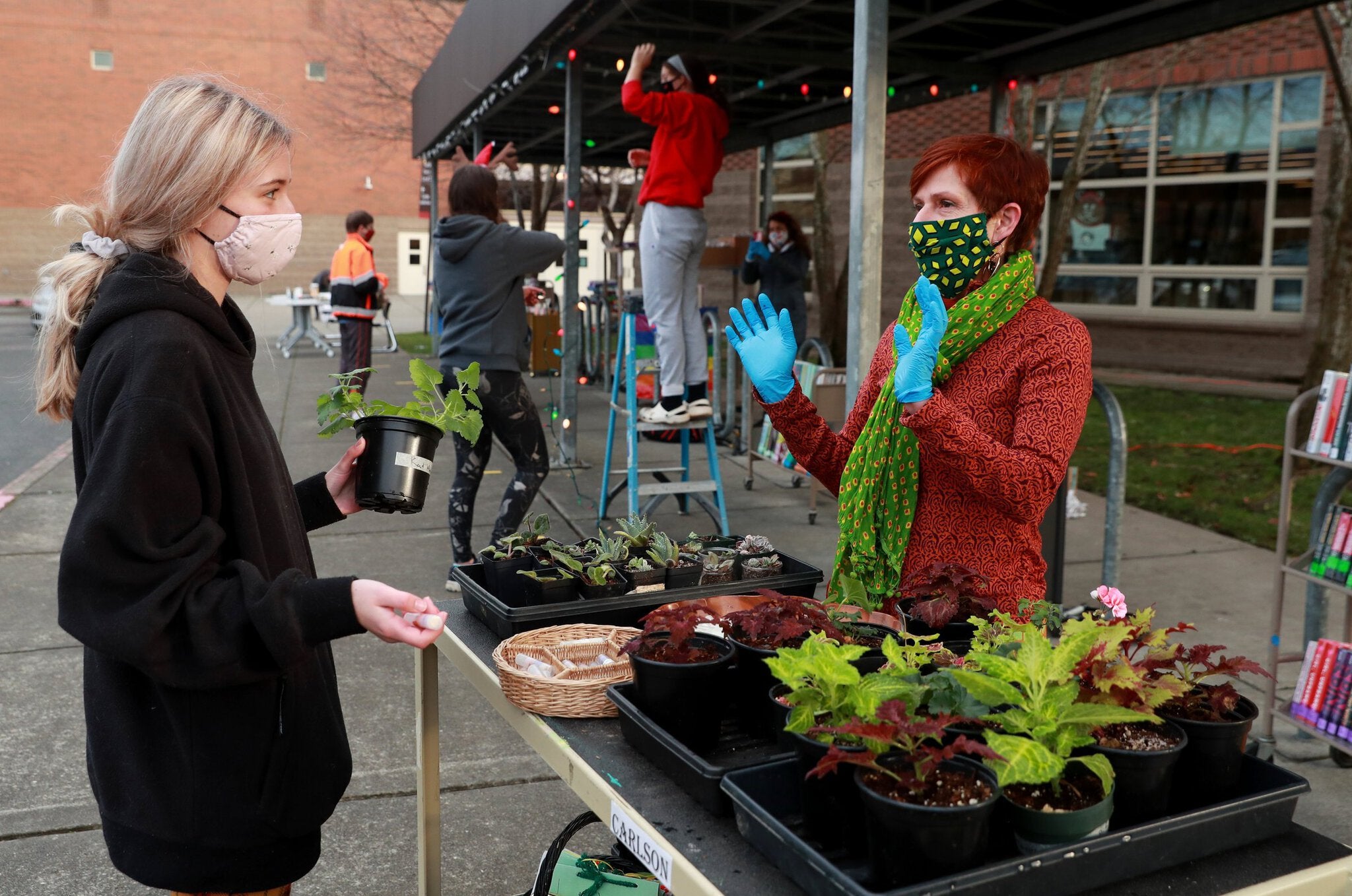 India Carlson, right, who teaches botany and environmental horticulture, speaks with Ballard High School student Norah Bunnell, 17, during a curbside pickup event at the school Dec. 10. (Erika Schultz / The Seattle Times)
