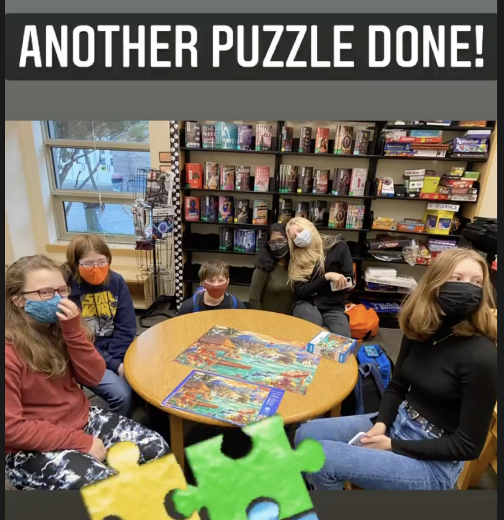 Students sitting at table working on puzzle in the library
